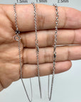 Three white gold chains of different thicknesses held against a hand.