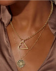Model wearing layered 14K gold necklaces with compass pendant and open heart charm