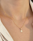 A dainty yellow solid gold twisted rope chain necklace with a mini Guardian Angel Medal Pendant, shown worn on a model's neck over a cream-colored collared shirt.