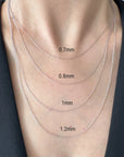 Close-up of a person's neck and upper chest wearing four layered white gold rope chains of different thicknesses, labeled 0.7mm, 0.8mm, 1mm, 1.2mm