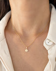 A dainty gold twisted rope chain necklace with a small Guardian Angel Medal, shown worn on a model's neck over a cream-colored collared shirt.