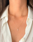 A delicate 14K Solid gold CZ cross pendant necklace worn by a model in a white collared shirt.