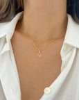 A close-up of a model wearing a dainty gold Hamsa hand pendant on 0.8mm twisted rope chain, styled with a white button-down shirt.