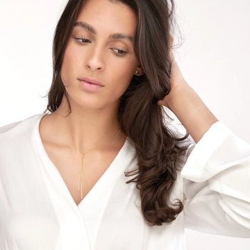Close-up of 14K gold drop bar lariat necklace on model