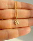 A delicate solid gold rope chain necklace with a small Guardian Angel Medal Pendant, held in the palm of a hand.