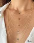 A close-up of a person's neck and upper chest wearing layered yellow gold twisted rope chain necklaces at different lengths, with printed size labels reading 16", 18", 20", 22", 24" and 1.2mm.