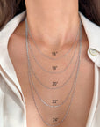 Close-up of a person's neck and upper chest wearing five layered 14k white gold figaro necklaces in different lengths, labeled 16", 18", 20", 22", and 24".